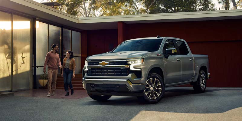 A silver Chevrolet Silverado parked in front of a modern home