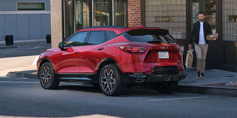 A red Chevrolet Blazer parked on a city street with a pedestrian