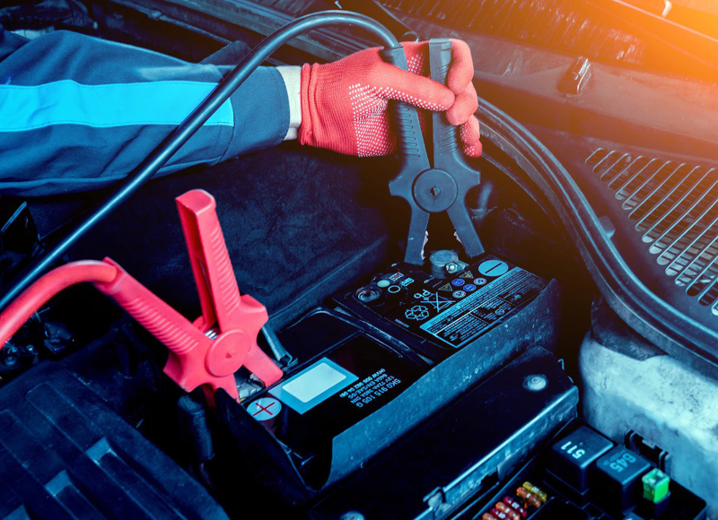 A technician using jumper cables to jump-start a car battery